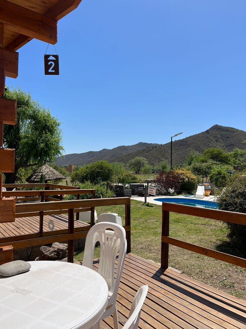 Galería de una cabaña con mesa, sillas y vista a las sierras