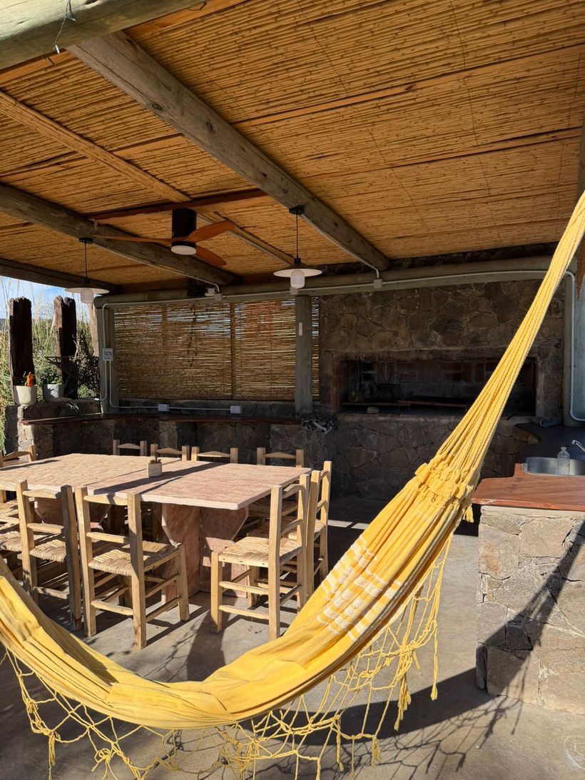 Quincho techado con mesa larga, parrilla y hamaca paraguaya
