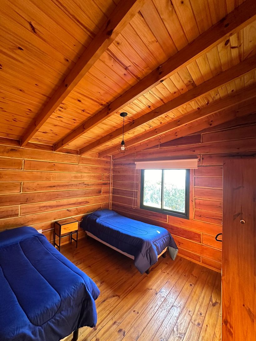Dormitorio con dos camas y piso de madera