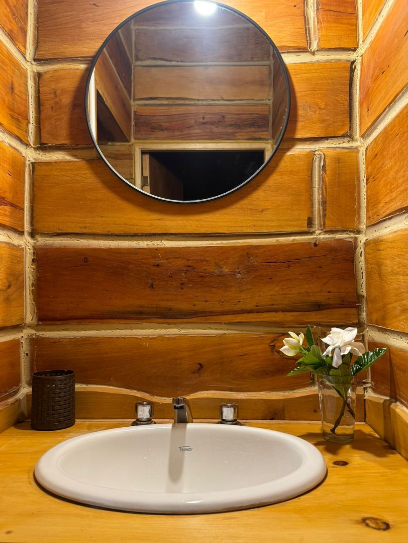 Baño de madera con lavabo y espejo redondo