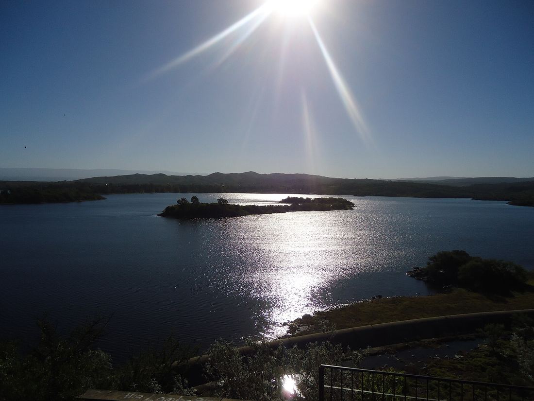 El lago Río Tercero con una isla, visto desde la costa al atardecer